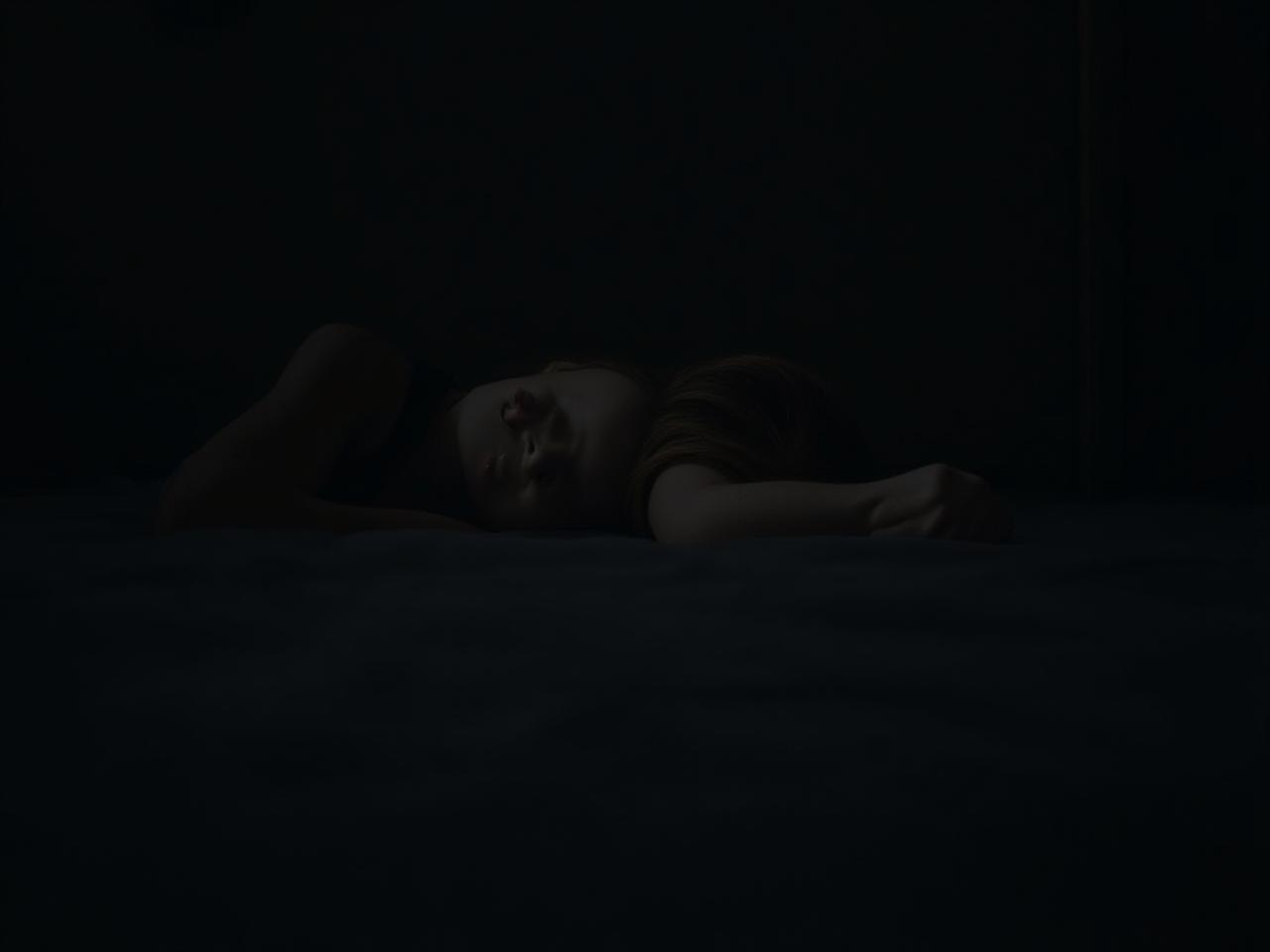 Person sleeping peacefully in a dark and cool room.
